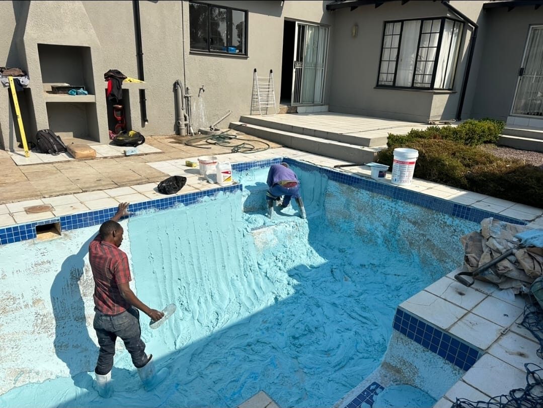 Technicians resurfacing a swimming pool with blue plaster in Randburg